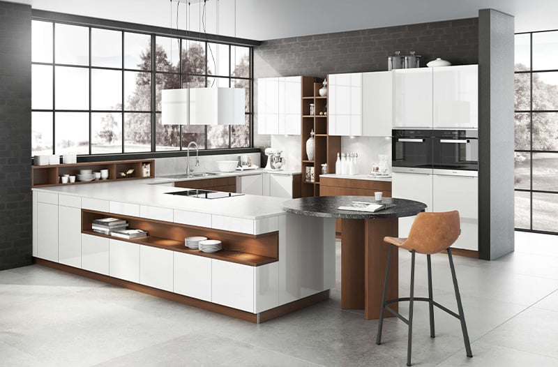 Modern kitchen with white cabinets, wood accents, and a breakfast bar with a brown chair.