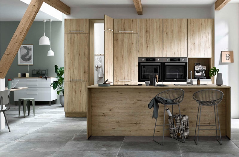 Modern kitchen with wooden cabinets, an island, and two bar stools. Dining area visible in the background.