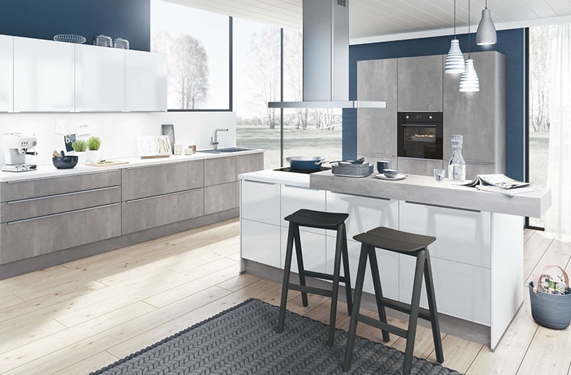 Modern kitchen with white cabinets, gray accents, and two black stools at a center island.