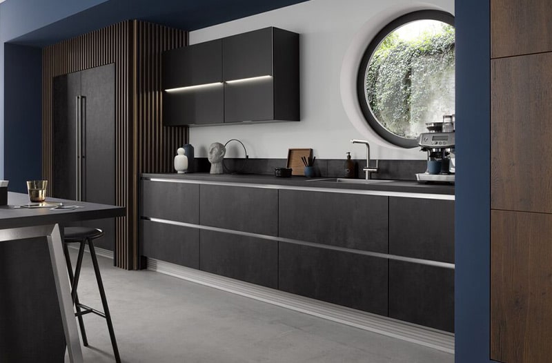 Modern kitchen with dark cabinets, a round window, and minimalist decor.
