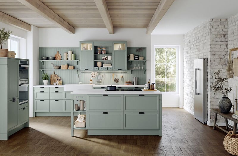 Modern kitchen with light green cabinets, island, wood floors, and exposed beam ceiling.