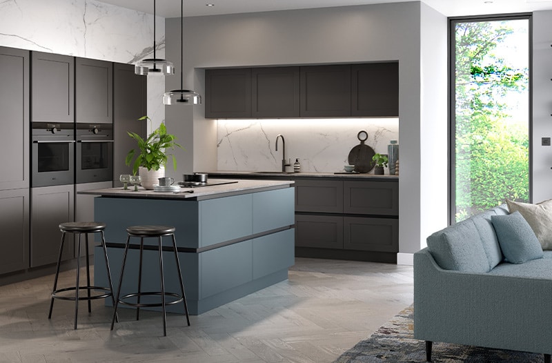Modern kitchen with grey cabinets, island, and bar stools, next to a window and a light blue sofa.