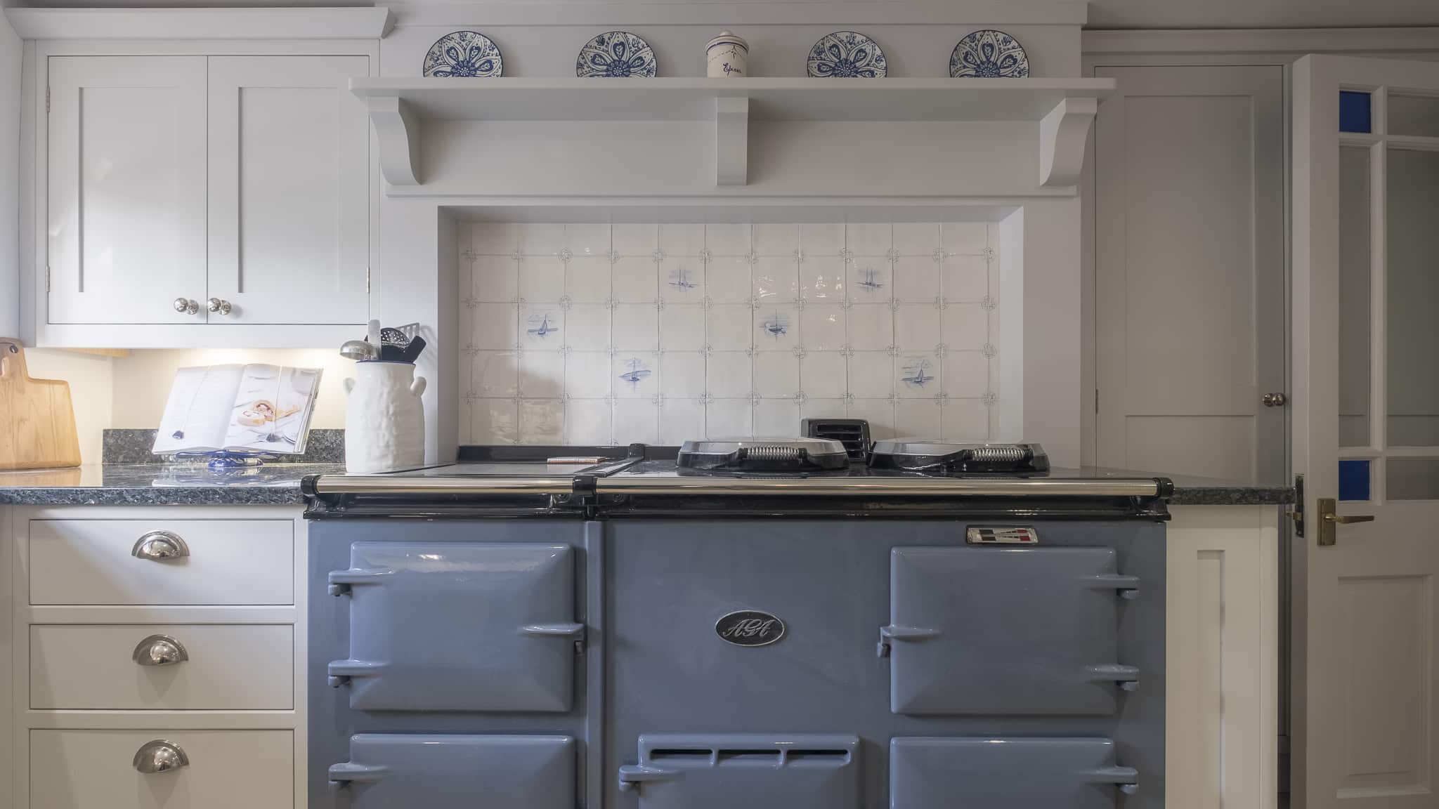 Light blue classic cooker with white cabinets and tiled backsplash in a traditional kitchen.