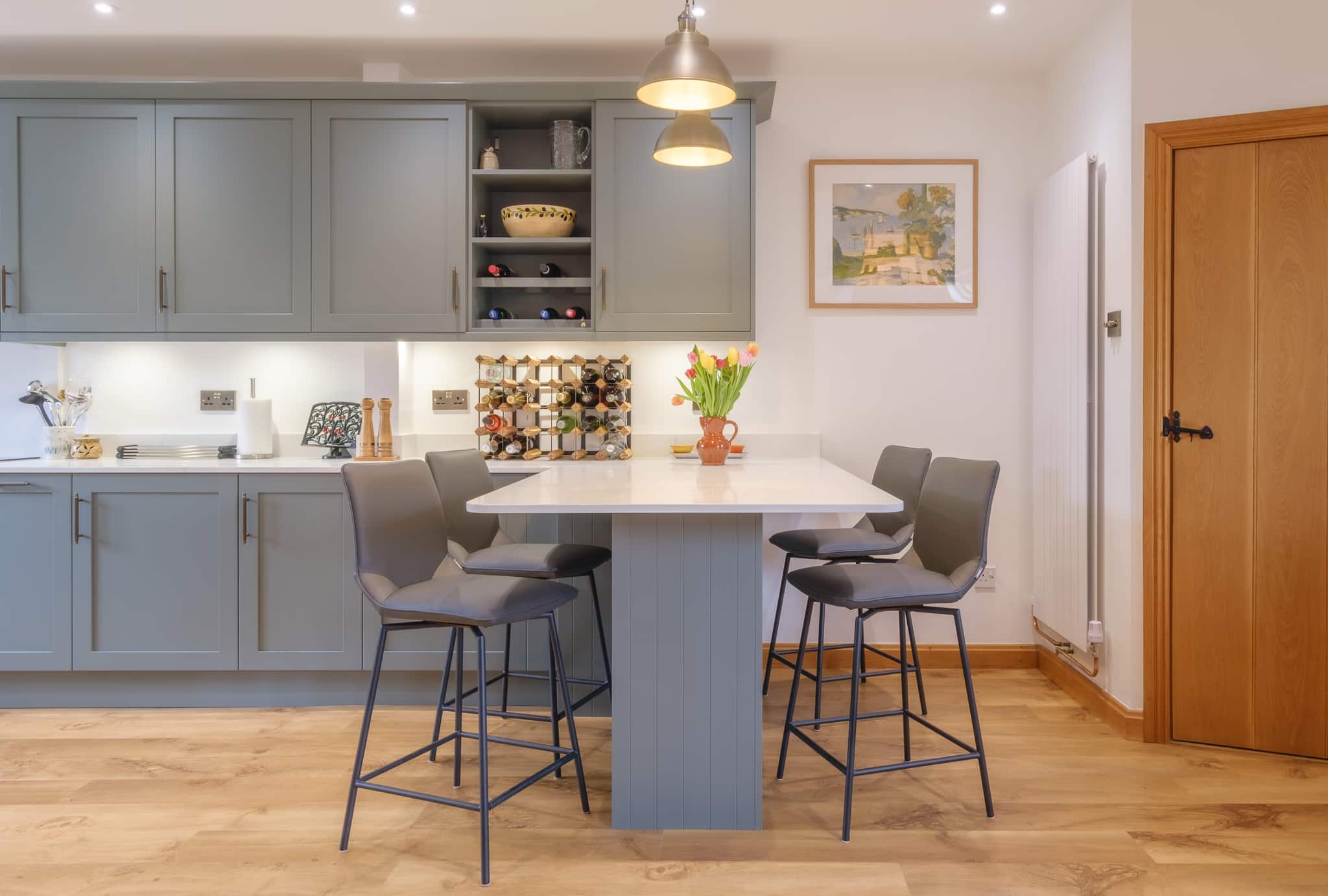 Modern kitchen with blue cabinets, island, bar stools, and pendant lights.