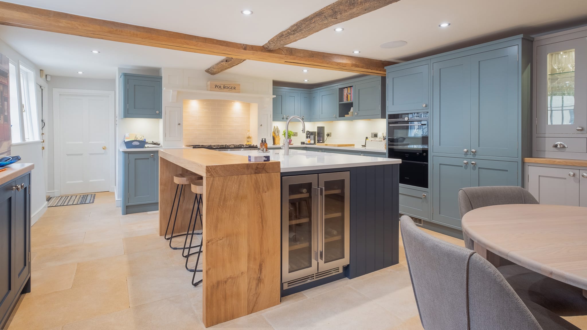 Modern kitchen with blue cabinets, wooden island, barstools, and a round dining table.