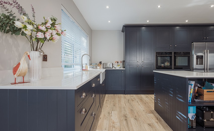 Modern kitchen with dark cabinets, light countertops, and wood flooring. Bright and tidy space.