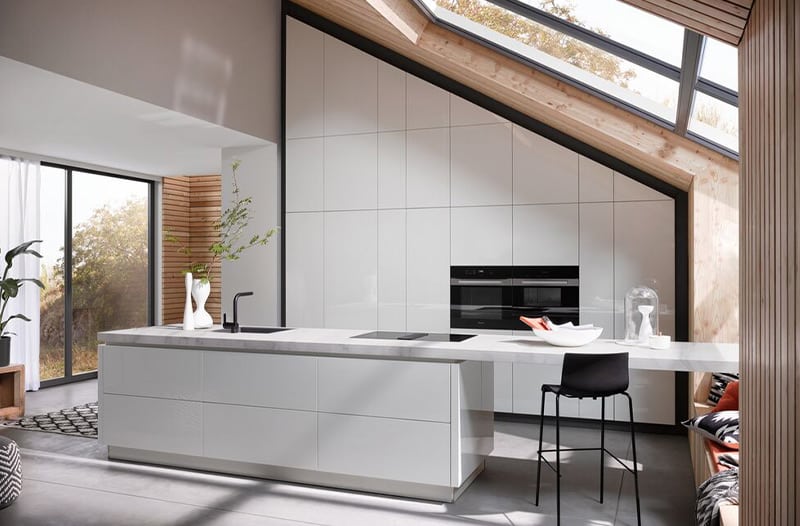 Modern kitchen with white cabinets, island, bar stool, and large windows letting in natural light.