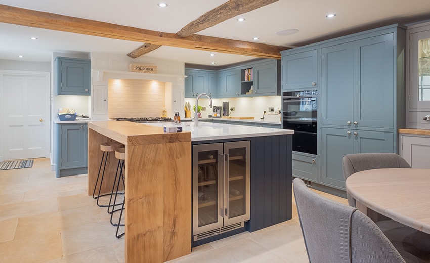 Modern kitchen with blue cabinets, wood accents, island seating, and integrated appliances.
