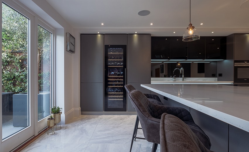 Modern kitchen with large island, bar stools, and glass doors leading to a patio.