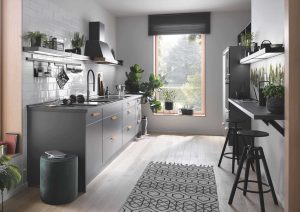 Modern kitchen with grey cabinets, plants, a window, and a breakfast bar with two stools.