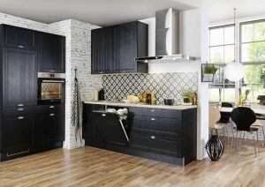 Modern kitchen with black cabinets, patterned backsplash, and a dining area by large windows.