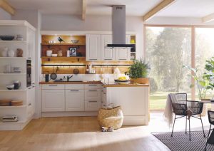 Modern kitchen with white cabinets, open shelves, and large windows overlooking a sunny garden.
