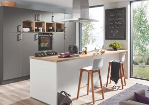 Modern kitchen with a central island, bar stools, large windows, and built-in appliances.