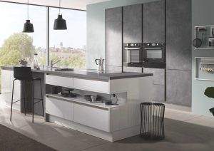 Modern kitchen with a large island, barstool, built-in ovens, and large windows.
