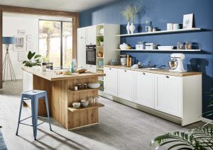 Modern kitchen with blue walls, white cabinets, wooden island, and open shelves with various kitchen items.