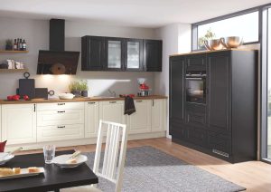 Modern kitchen with black and white cabinets, wooden countertop, and large windows.