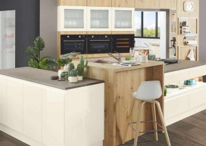 Modern kitchen with white cabinets, a wooden island, plants, and a white barstool.