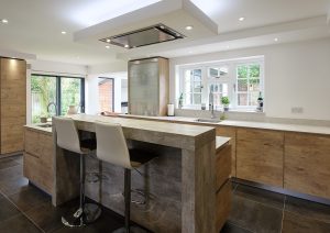 Modern kitchen with wood cabinets, island seating, and large windows letting in natural light.