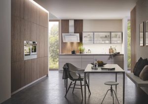 Modern kitchen with wood cabinets, built-in appliances, and a dining table with chairs.