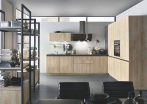 Modern kitchen with light wood cabinets, open shelving, and black chairs around a dining table.
