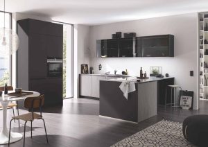 Modern kitchen with dark cabinets, an island, and a dining table in a bright, open space.