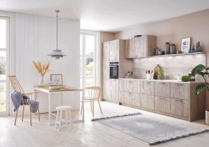 Modern kitchen with light wood cabinets, dining table, chairs, large windows, and indoor plants.