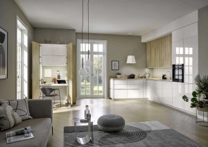 Modern kitchen and living room with natural light, white cabinets, and a home office nook.