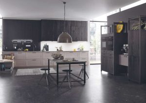 Modern kitchen with dark cabinets, a small dining table, and large windows letting in natural light.
