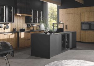 Modern kitchen with wooden cabinets, black island, built-in ovens, and large window.