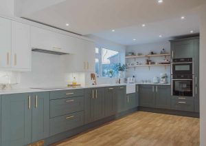 Modern kitchen with grey and white cabinets, wooden floor, and built-in appliances.