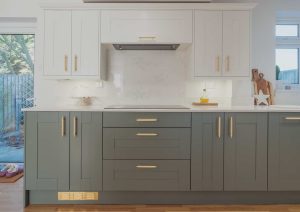 Modern kitchen with white upper cabinets, green lower cabinets, and gold handles.