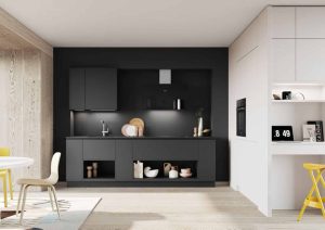 Modern kitchen with dark cabinets, open shelves, and a small white desk area with a yellow stool.
