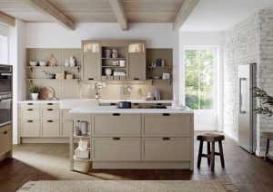 Modern kitchen with beige cabinets, island, wooden beams, and sunlight coming through a glass door.
