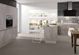 Modern kitchen with gray cabinets, island seating, and a dining table with white chairs.