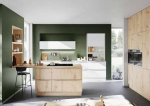 Modern kitchen with green walls, wooden cabinets, and white countertops.