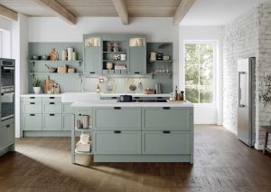 Modern kitchen with light green cabinets, wooden floor, and a large window letting in natural light.