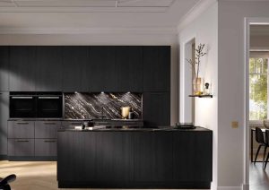 Modern kitchen with dark cabinets and an island, featuring a marble backsplash and built-in ovens.