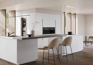 Modern white kitchen with an island, bar stools, and built-in appliances in a bright open space.