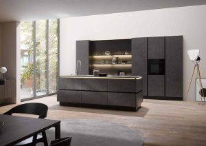 Modern kitchen with dark cabinets, island, open shelves, and large window letting in natural light.