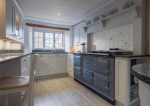 A cozy kitchen with white cabinets, a large stove, and a window letting in natural light.