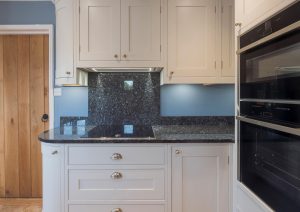 Modern kitchen with white cabinets, black countertops, and built-in double ovens.
