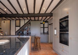Modern kitchen with wooden beams, grey cabinets, and a black countertop.