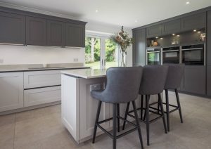 Modern kitchen with gray cabinets, island seating, and large windows letting in natural light.