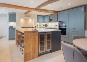 Modern kitchen with blue cabinets, wooden island, built-in wine cooler, and dining table with chairs.