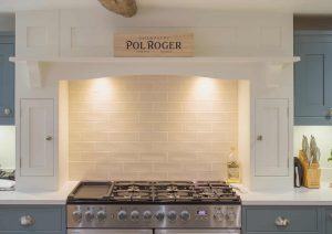 Modern kitchen with a stainless steel stove, blue cabinets, and tiled backsplash under warm lighting.