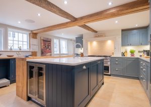 Modern kitchen with blue cabinets, a large island, and exposed wooden beams on the ceiling.