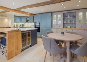 Modern kitchen with wooden island, round dining table, and grey cabinets.