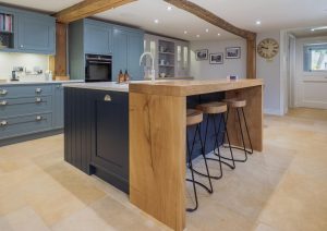 Modern kitchen with blue cabinets, wood accents, and a large island with bar stools.