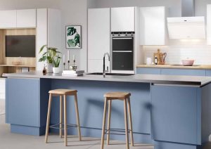 Modern kitchen with blue island, two wooden stools, white cabinets, and built-in appliances.