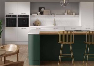 Modern kitchen with white cabinets, a green island, and gold bar stools.